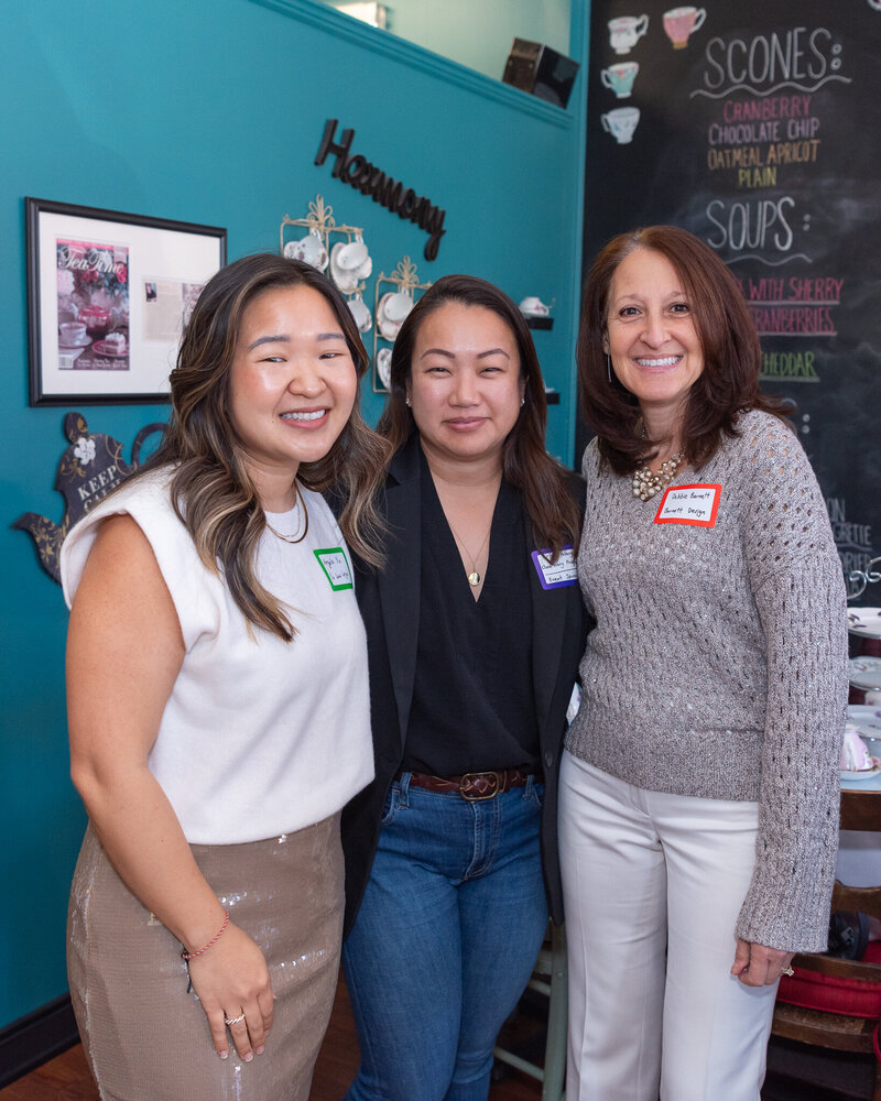 A group of women smiling and posing for a group shot at a high tea networking event.