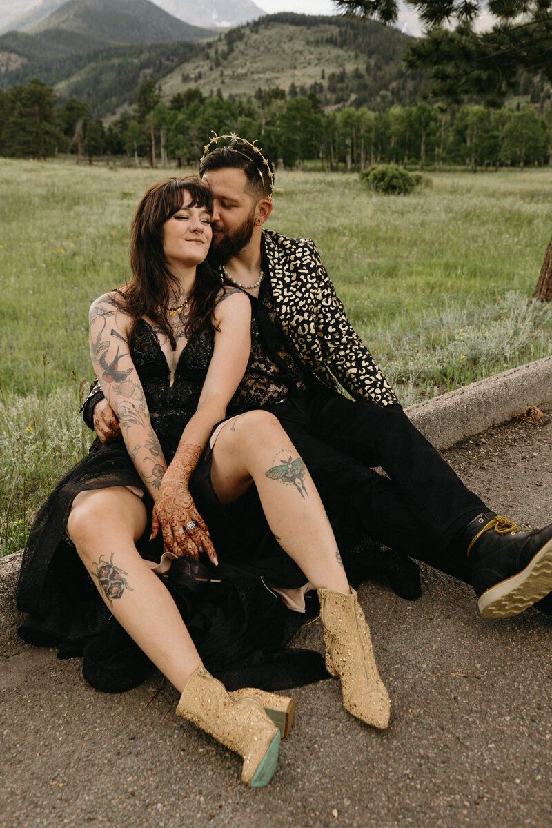 wedding couple wearing black on their wedding day sitting on the side of the street in Rocky MOuntain National Park