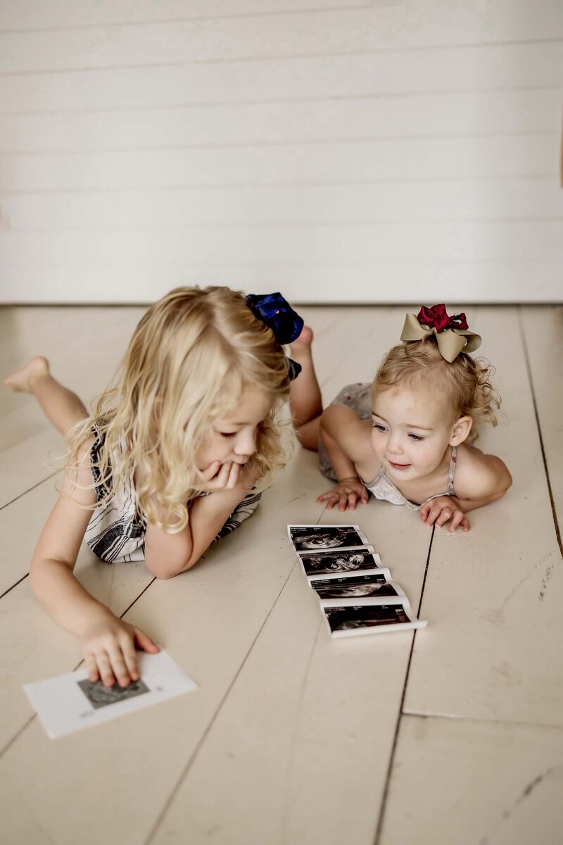 two sisters look a the sonogram images of their new sibling on the way.