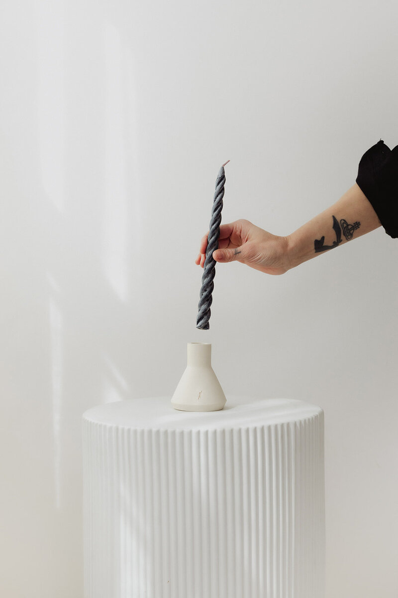 a hand placing a candle stick into a candle holder