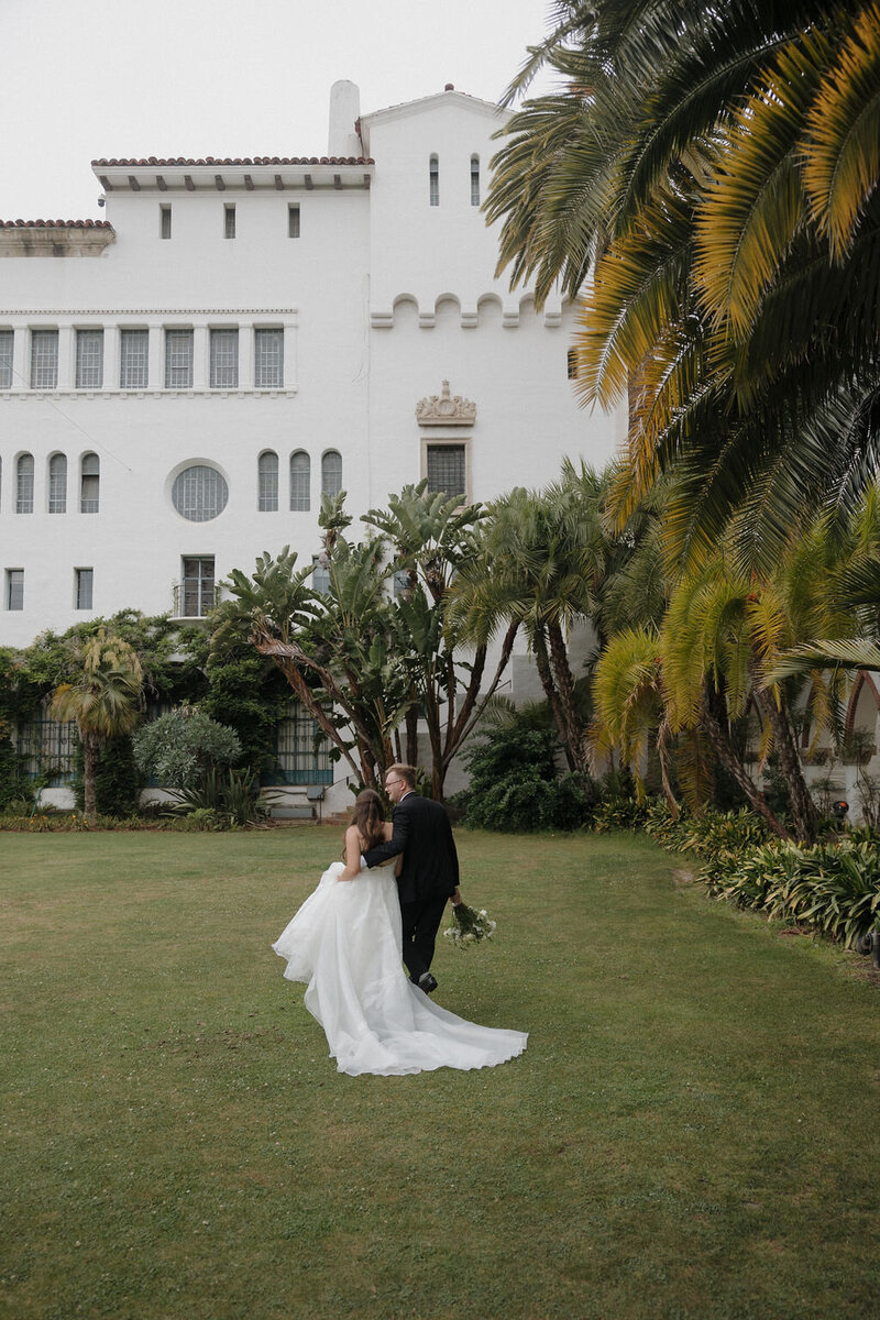 Bride and groom walking candid image at Santa Barbara Courthouse Sunken Gardens during elopement