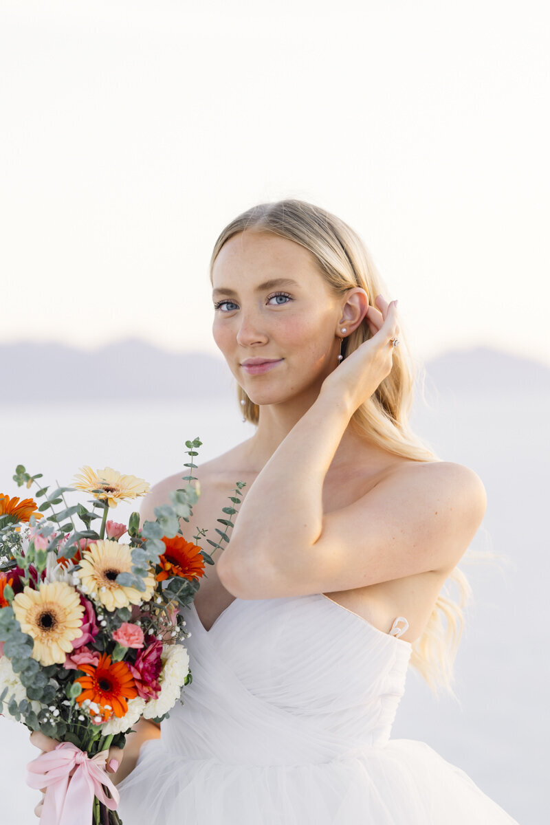 bride touching her hair while holding a bridal bouquet