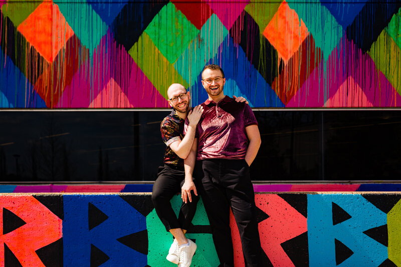 Two grooms embracing in front of the RGB mural in Toledo Ohio