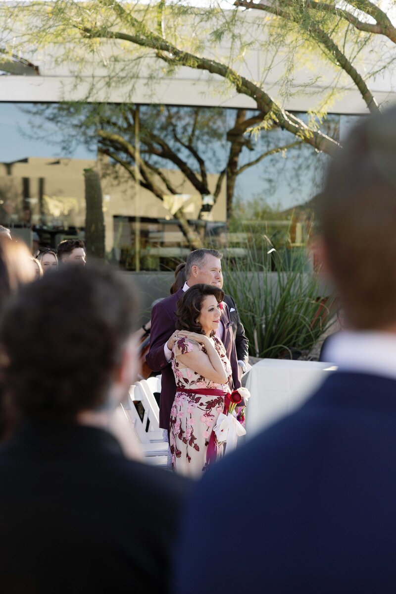 Bride’s parents cuddle as they watch their daughter get married.