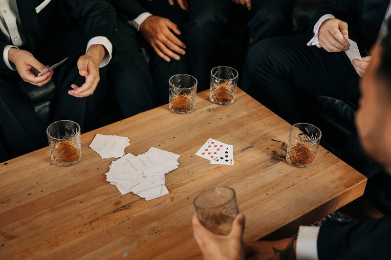 groom and groomsmen play cards with whiskey at the winehouse wedding venue in queenstown