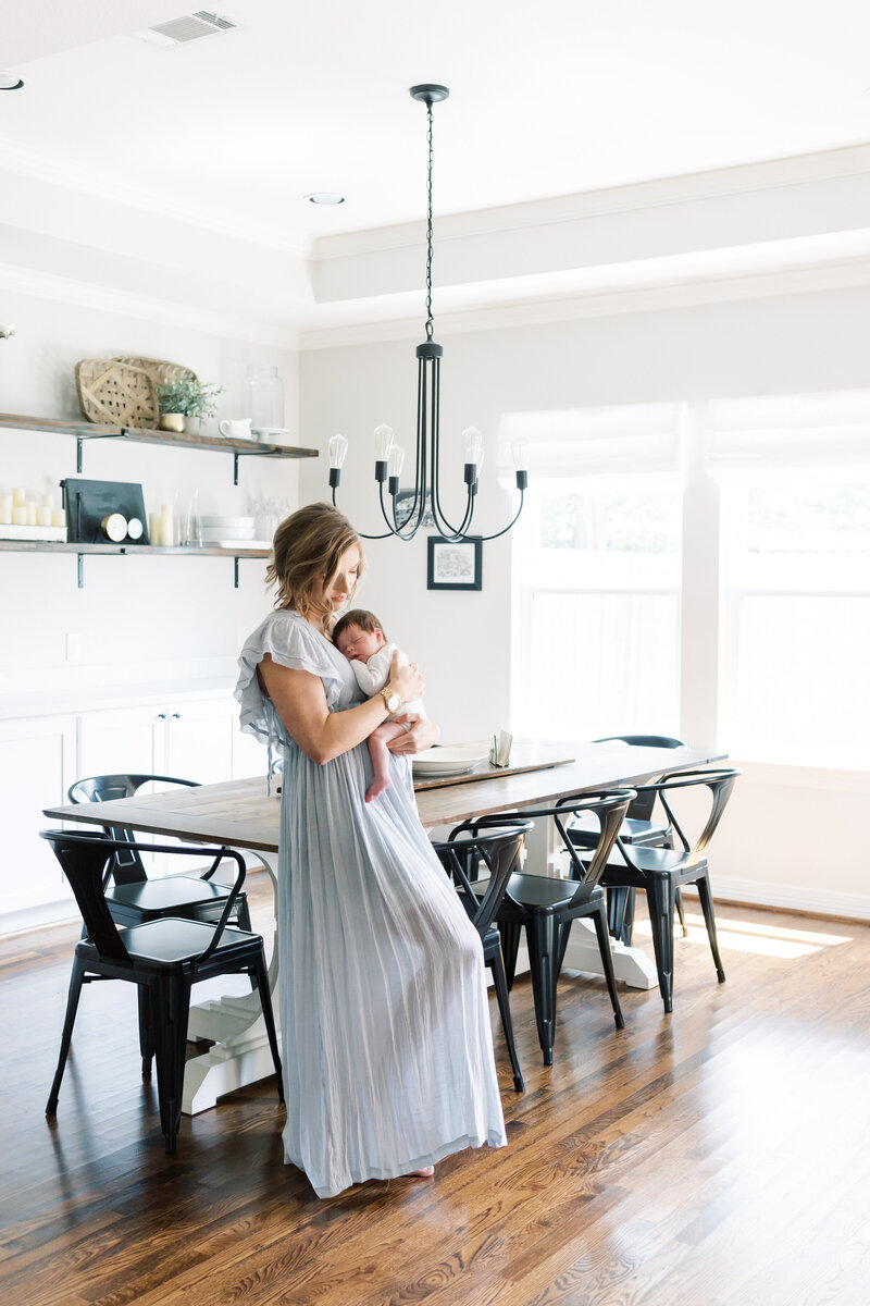 a mom holding her baby in a dining room