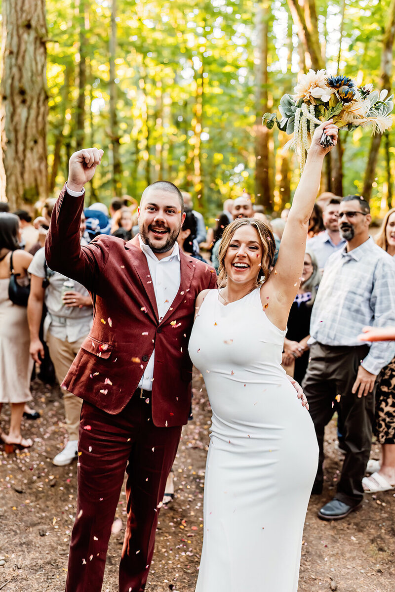 a micro seattle wedding couple in a forest after their ceremony with their people throwing confetti over them