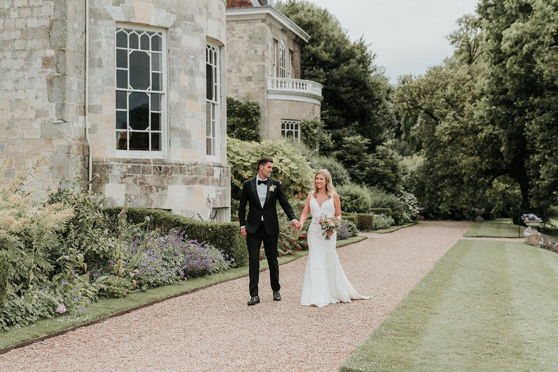 Bride and Groom walk hand in hand along cobbled pathway at Firle Place, East Sussex