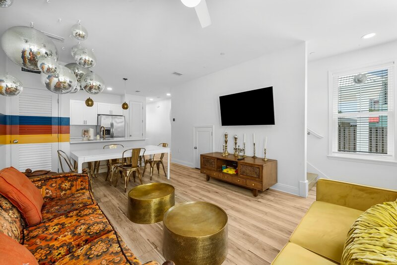 Spacious open-concept living and dining area with bold 70s style and gold accents in Groovy Shack, located minutes from Pier Park