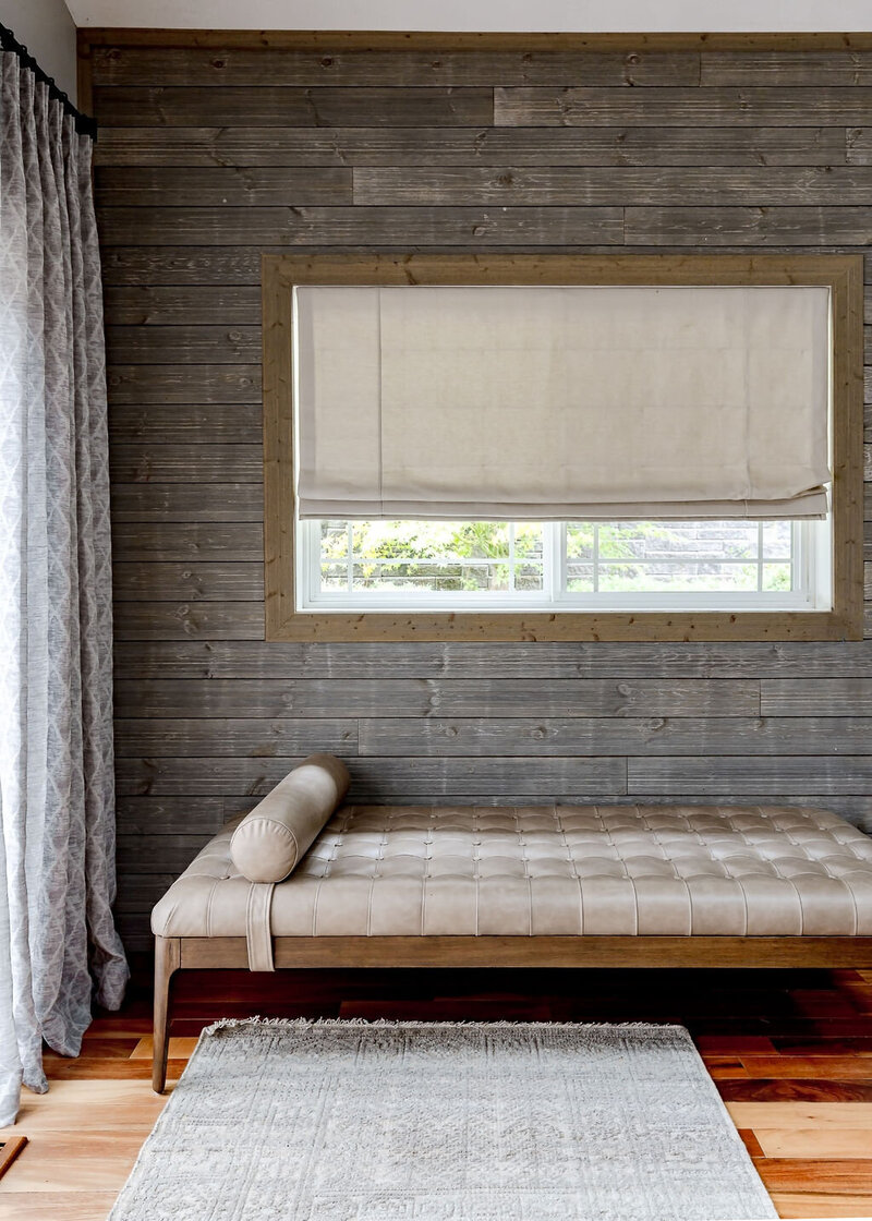 A nordic interior design featuring a weathered timbered wall with a window and seating below it.