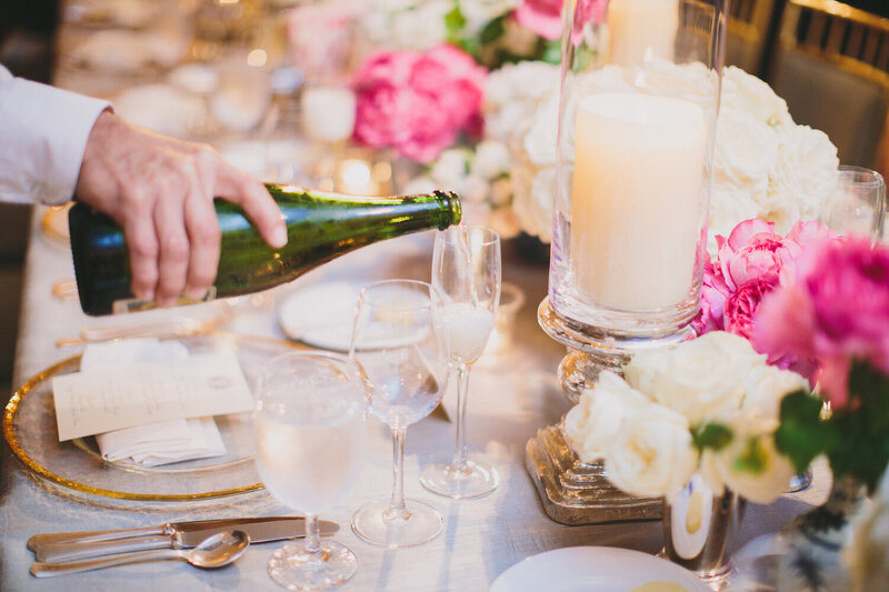 wedding table of pink and white flowers with waiter pouring champagne in glass