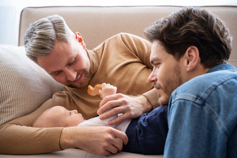 Two dads holding their baby after utilizing Blue Sky Fertility for fertility care