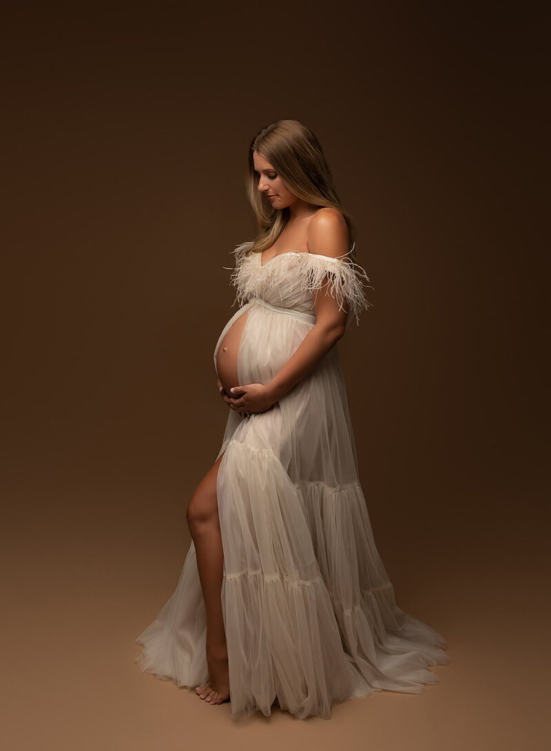 Feathered strapless maternity look in warm studio lighting