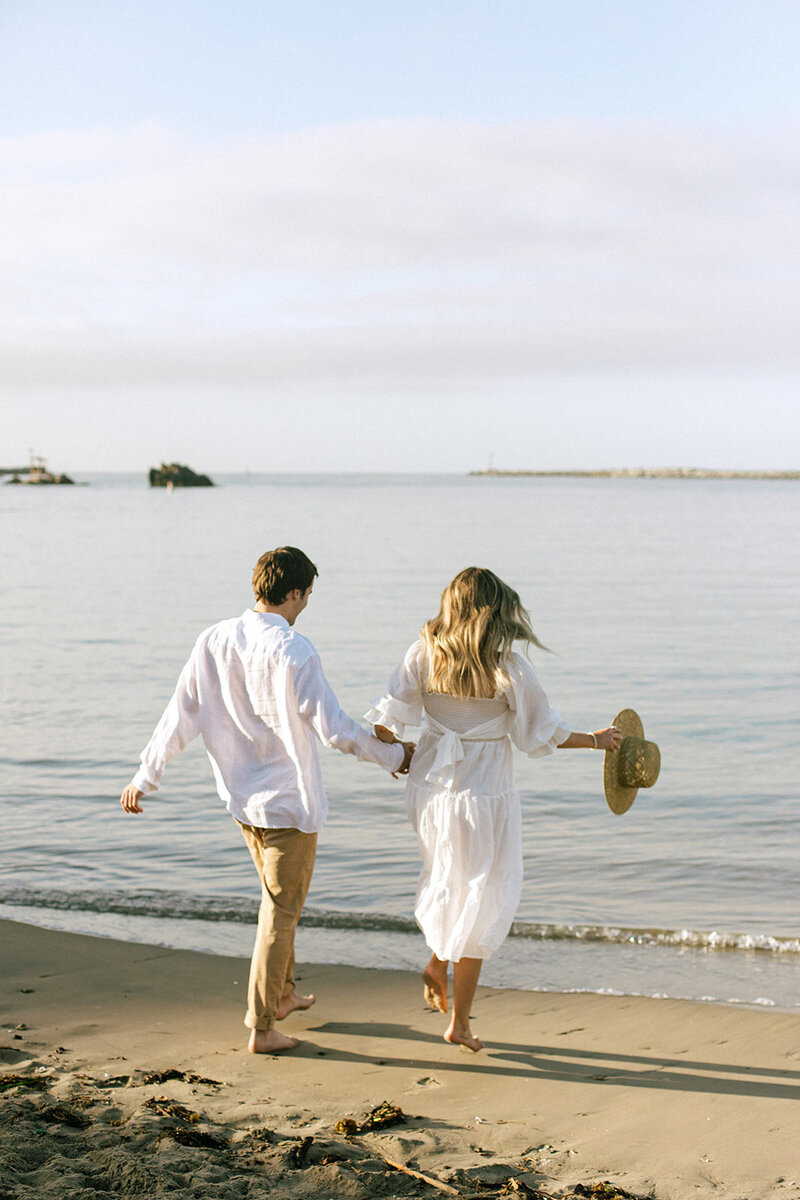 a couple walking on the beach during an engagement photoshoot