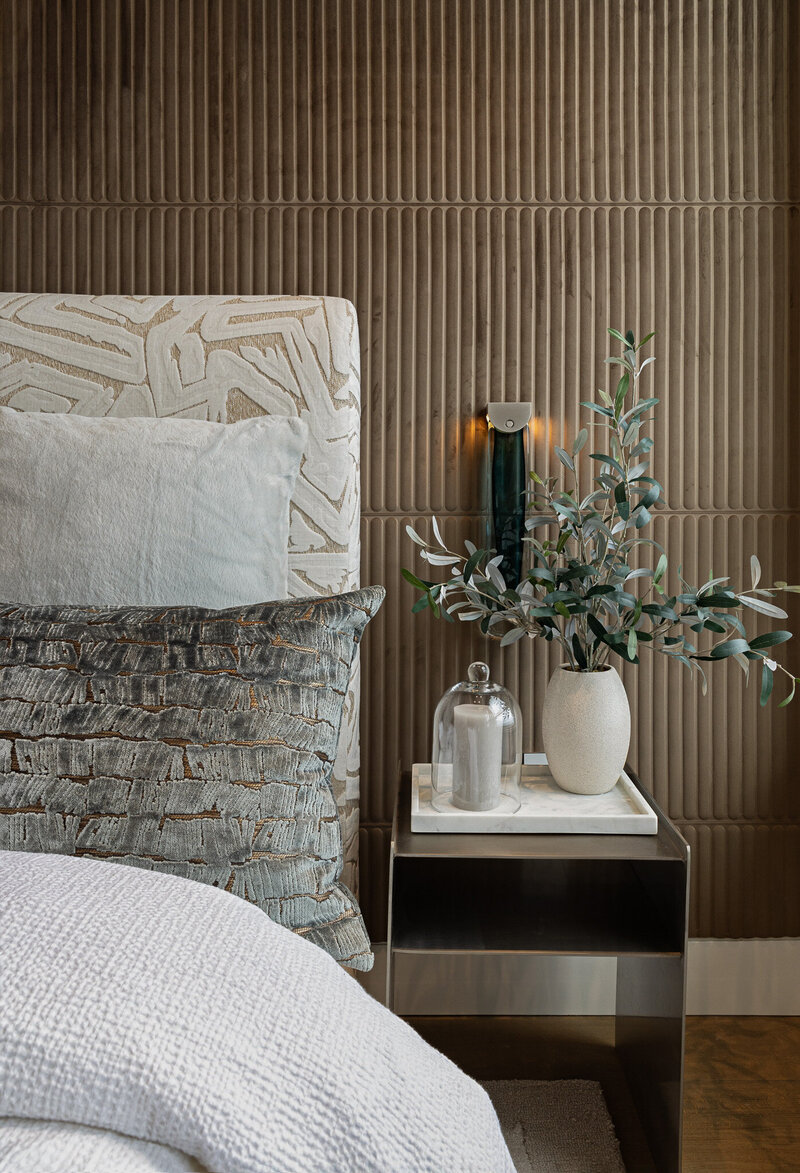 A detail image of a luxury modern guest bedroom with chocolate brown wallpaper, a textured bedframe, and a styled metal nightstand. In downtown Salt Lake City, Utah by Sister Studio Interior Design.