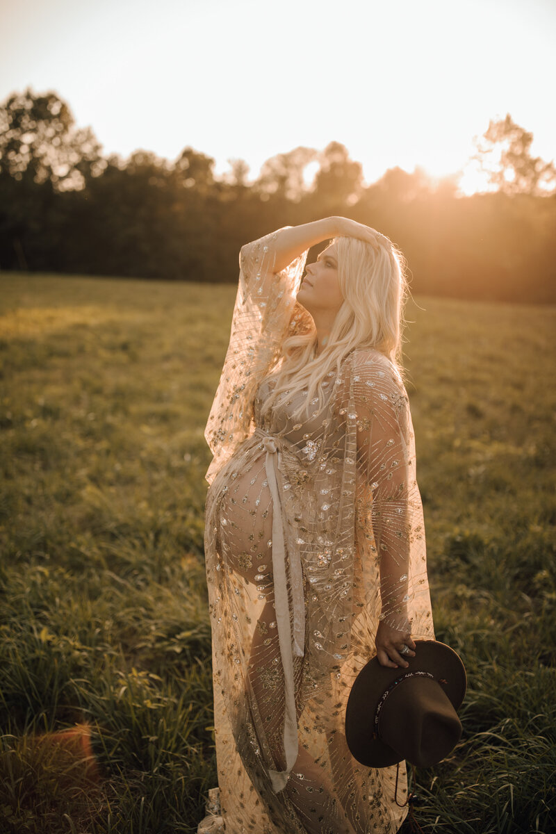 maternity session in a field wearing a sheer dress