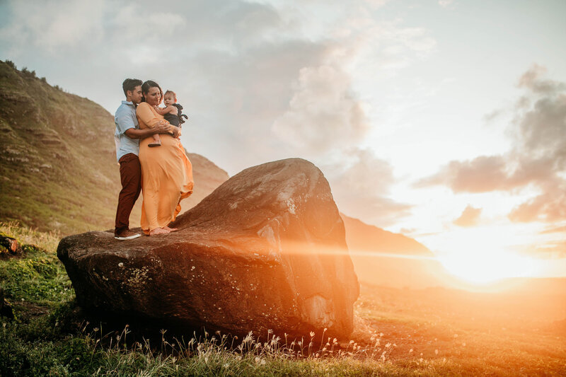 family hugging during sunset on a boulder in Hawaii