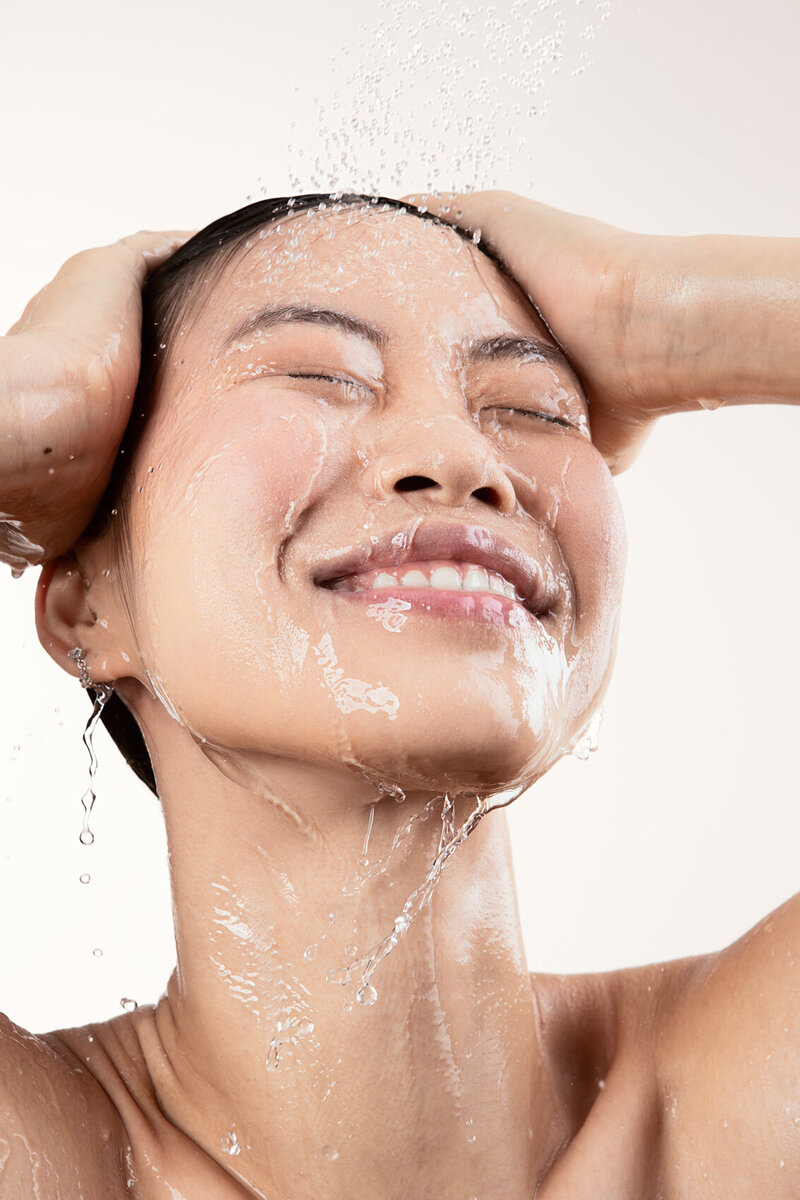 Jiaqi in a refreshing beauty shot, smiling with water splashing over her face, captured in a moment of joy by Ylva Erevall.