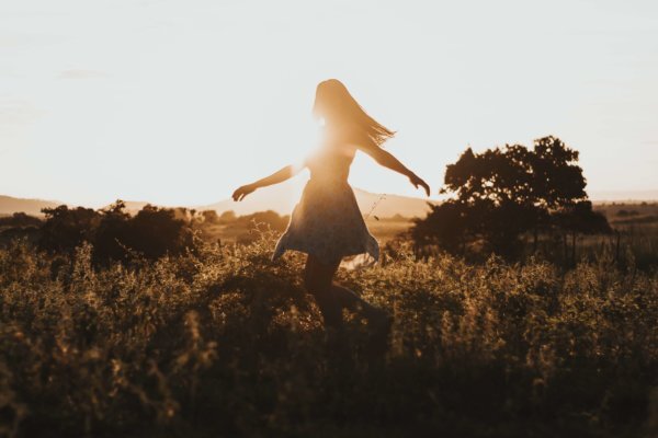 Stock photo of a woman dancing in a sunlit field, representing joy and positive results from hormone therapy at Wellness & Hormone Health in Centennial, Colorado.