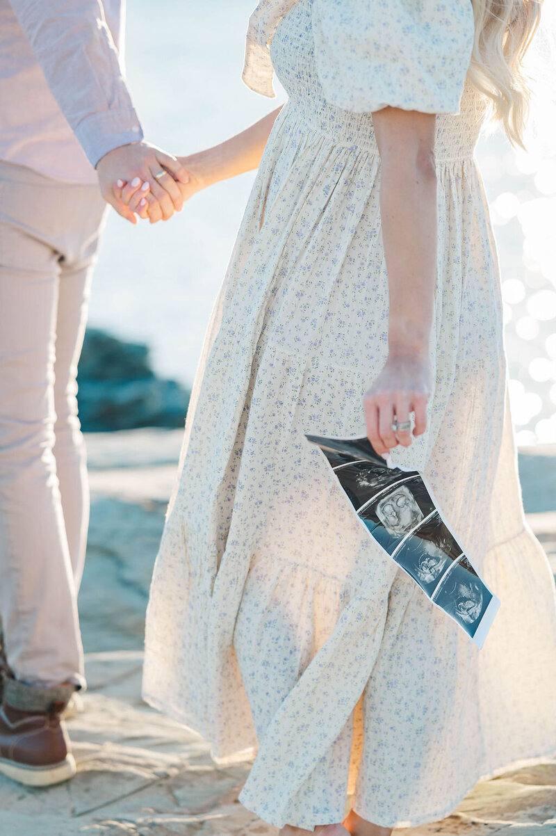 Pregnant woman holding sonogram for baby announcement photos in Newport, RI