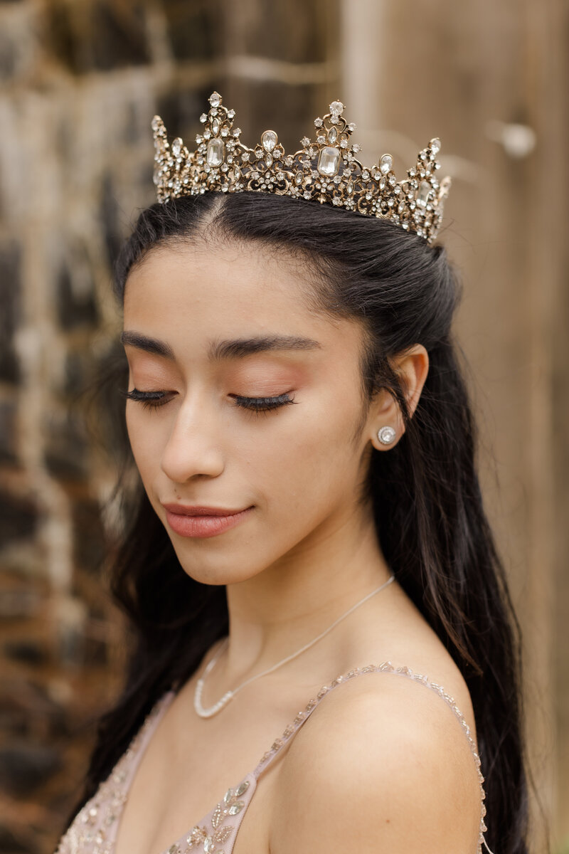 woman in quinceanera dress standing in front of large stone building
