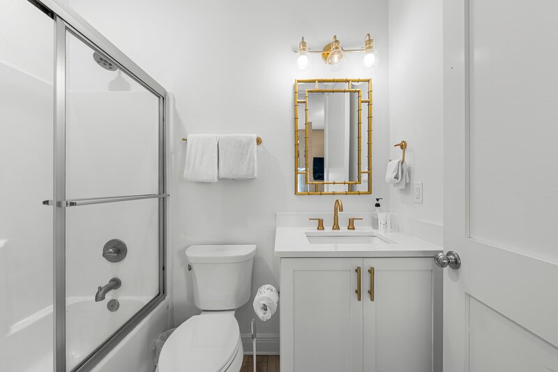 Chic full bathroom with gold accents and walk-in shower at Beach Cabana vacation rental in Panama City Beach, near 30A and Santa Rosa Beach.