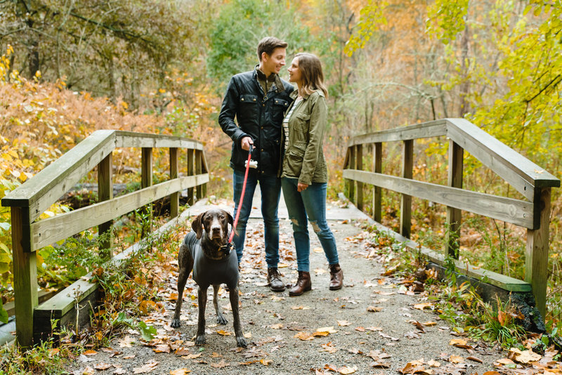 engaged couple walking dog during fall engagement session