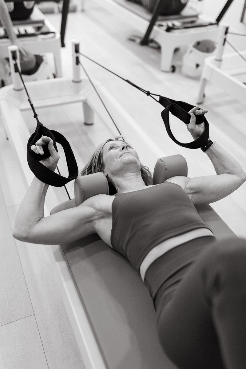 A man is in a pilates pose with his legs wide apart and arms stretched out.