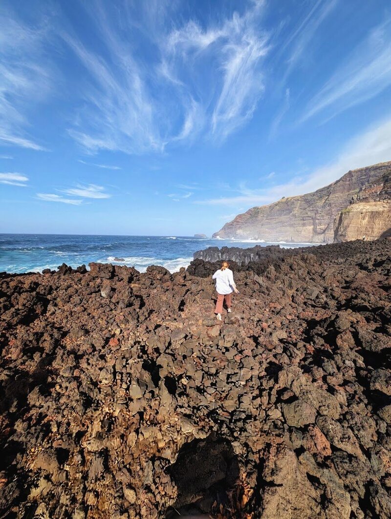 Woman walking across cliffs beside the ocean