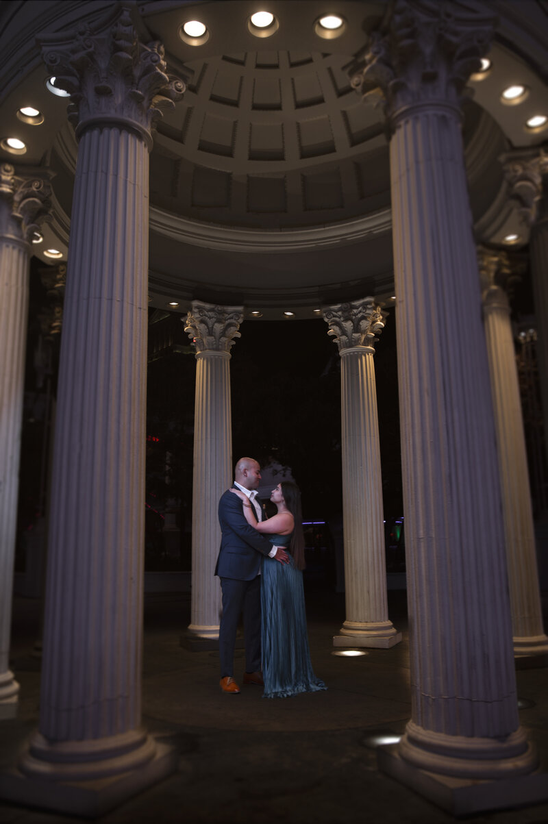 Couple embracing and dancing between tall stone columns at night in Lincoln, Nebraska, captured by Legacy in Light Photography.