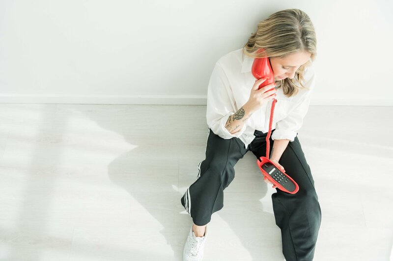Dallas web design expert for small businesses talking on the phone, dressed in a professional white and black outfit, showcasing creative services for local entrepreneurs.