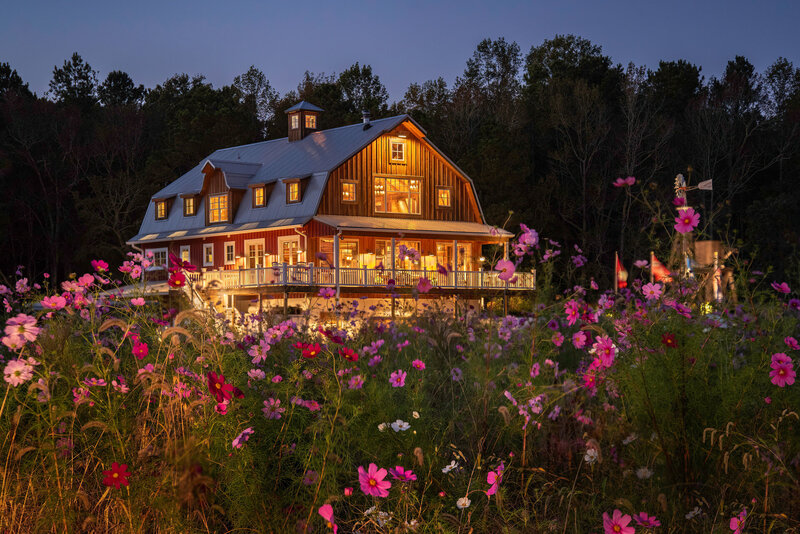 Creative twilight photography  of a vacation rental home in Berlin Maryland. Home photographed at night with all lights on  from the field of cosmos flowers.