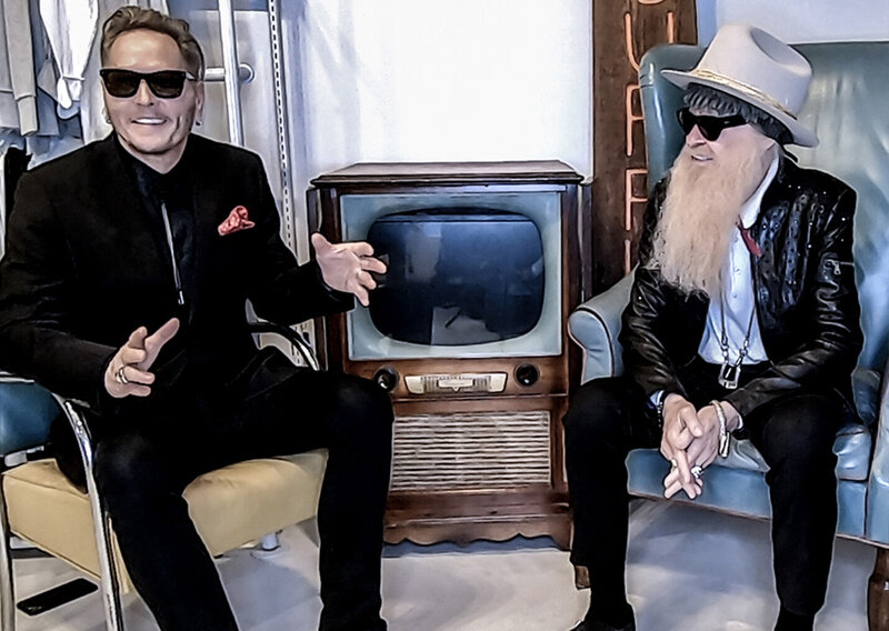 Matt Sorum Billy F Gibbons Guest Webisode One The Art of Giving Matt smiling and gesturing while Billy watches him while both seated