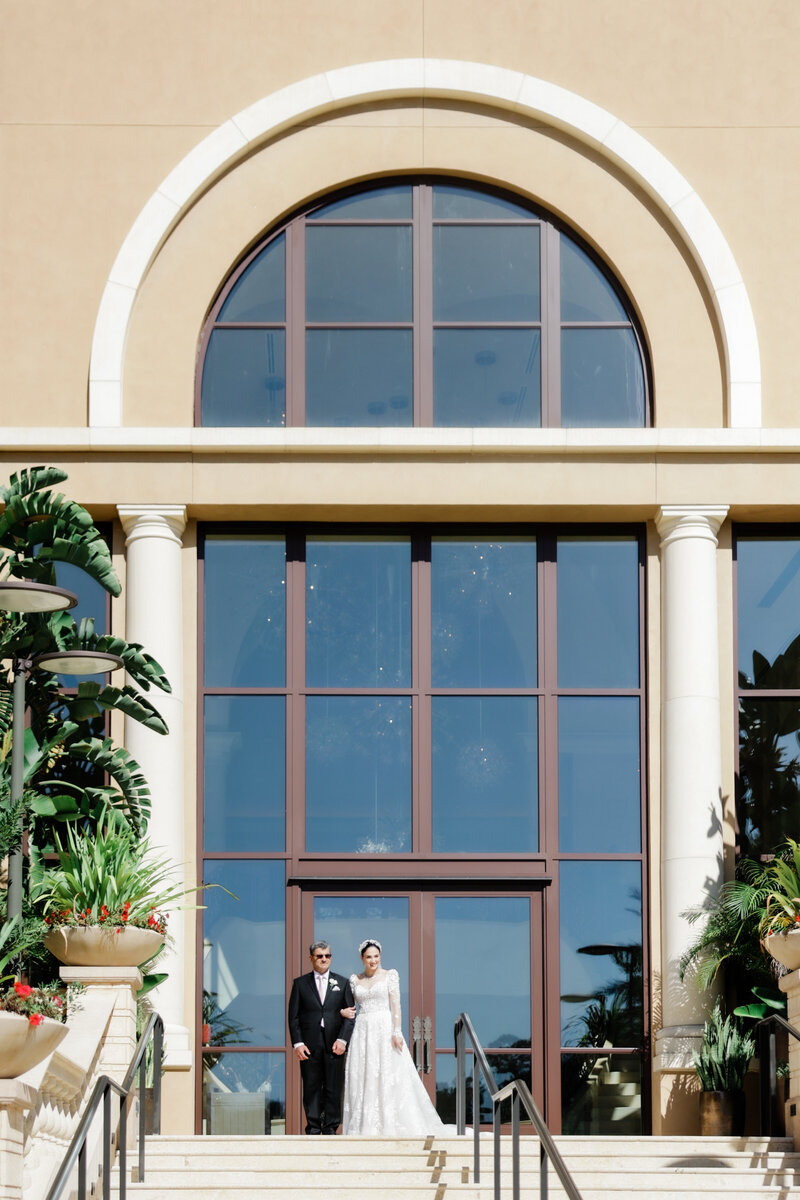 Bride and her father coming down the grand staircase for the couples first look at a wedding at the four seasons Orlando by Florida wedding photographer.