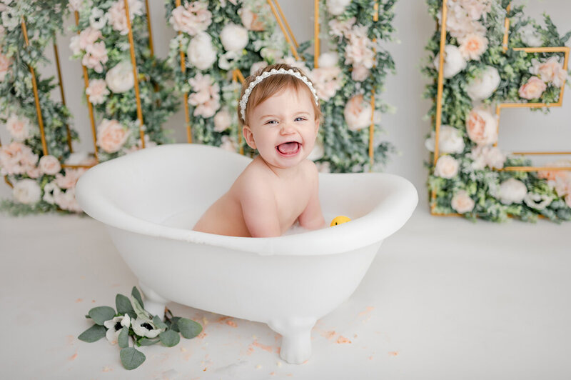 Baby girl smiling in bathtub after cake smash.
