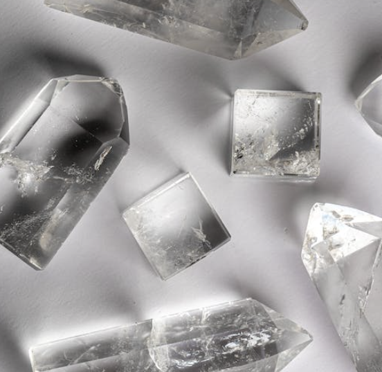 Several multi-shaped crystal quartz stones lay on white table