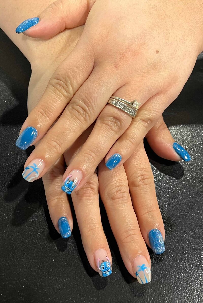 A set of blue nails with palm trees on one nail and the disney character "Stitch" on another nail
