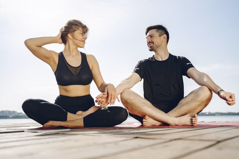 Couple holding hands while sitting on yoga mats