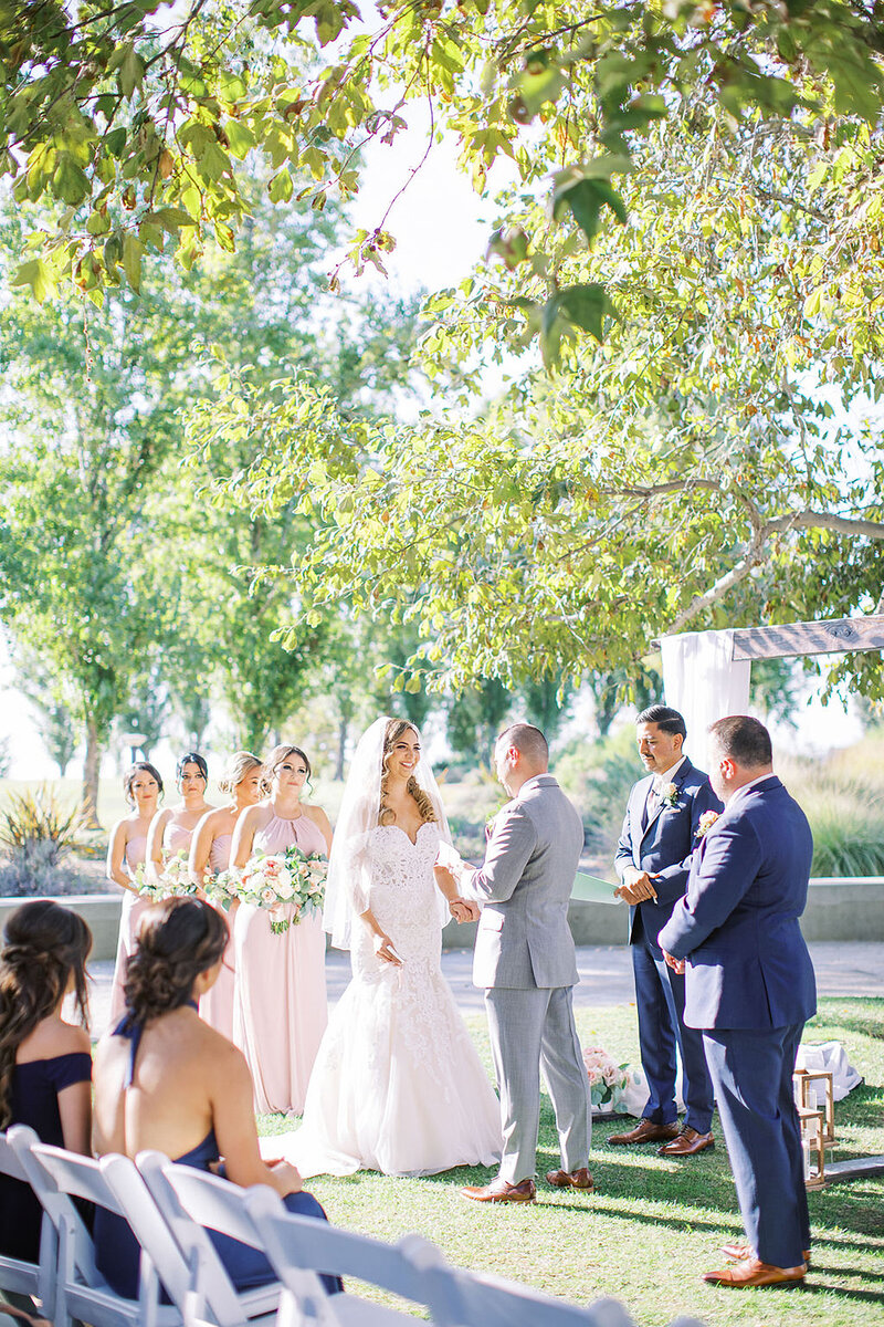 6-radiant-love-events-bride-groom-outdoor-ceremony-greenery-groom-saying-vows-romantic-elegant-timeless