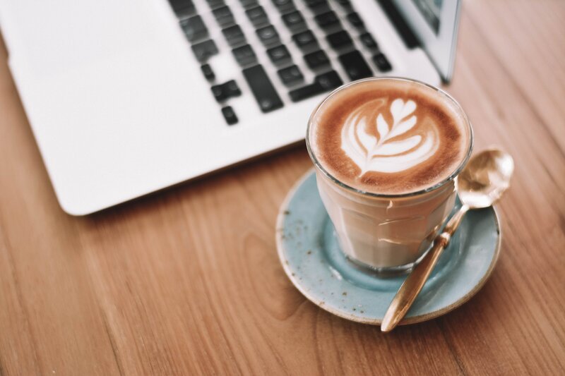 Latte on a table next to a laptop