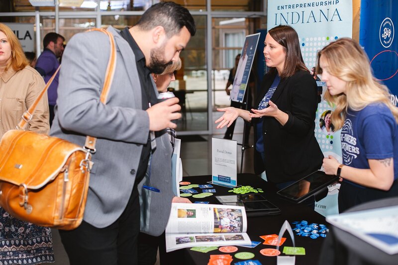  a-businesswoman-at-a-corporate-networking-event-speaking-to-an-attendee-at-an-exhibit-booth-during-a-business-conference-in-indianapolis-Fast-turnaround-with high-quality-professionally -edited- images