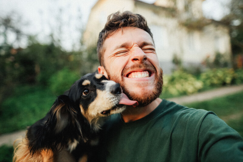 Smiling man with his dog licking his face — Roxi & Co Sioux Falls dog food and supplies.