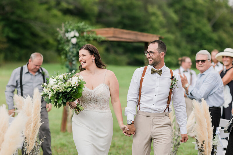 Couple holding hands walking down aisle after saying i do