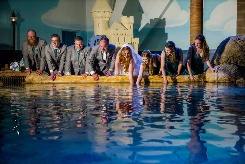 Bridal party having fun at the Sting Ray Beach Club exhibit at Adventure Aquarium, adding a playful twist to their unique wedding.