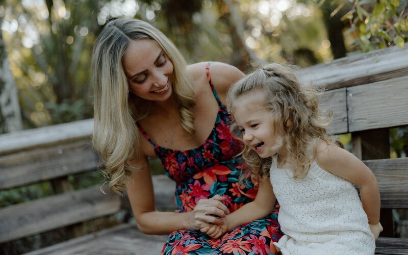 mother and daughter hold hands and laugh during family photoshoot in south florida