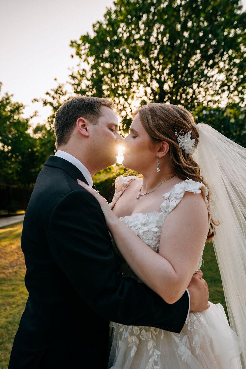 Bride and groom kissing at sunset