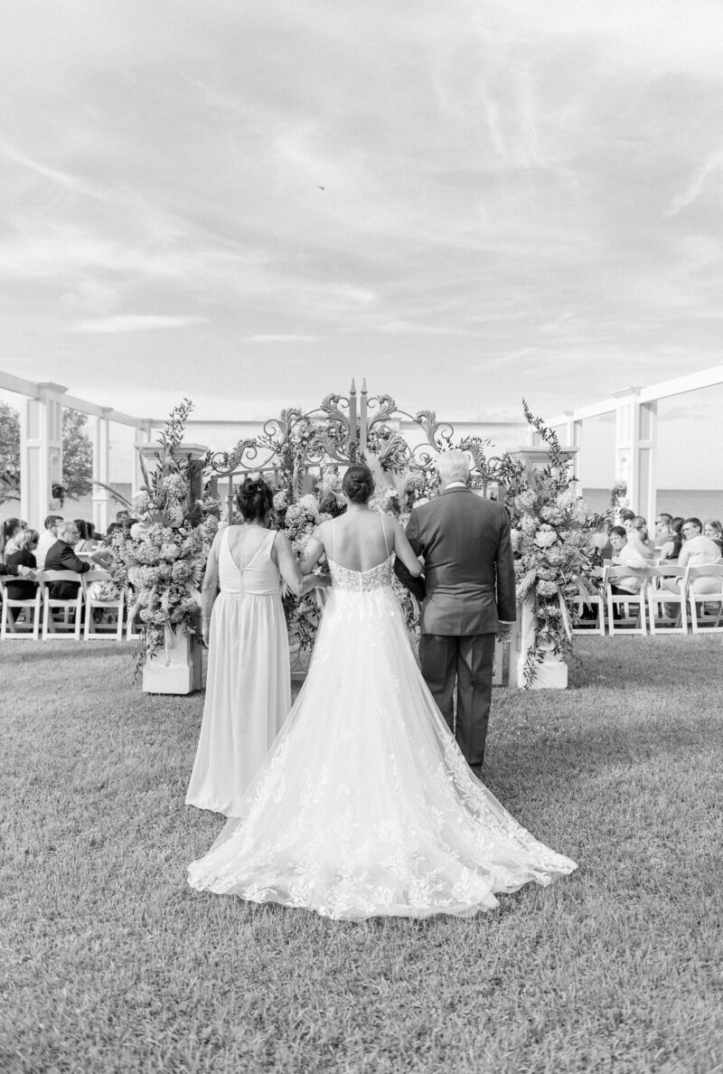 Mom and dad walk daughter down the aisle for wedding ceremony.