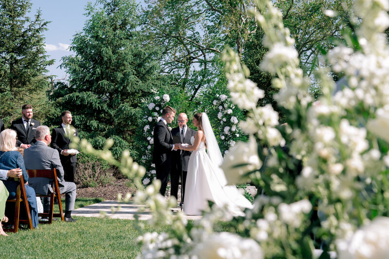 A couple says their vows surrounded by white roses at a luxury manor in Grand Rapids