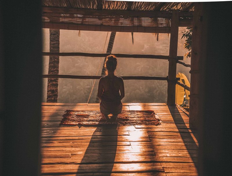 Women on yoga platform on knees facing sunset