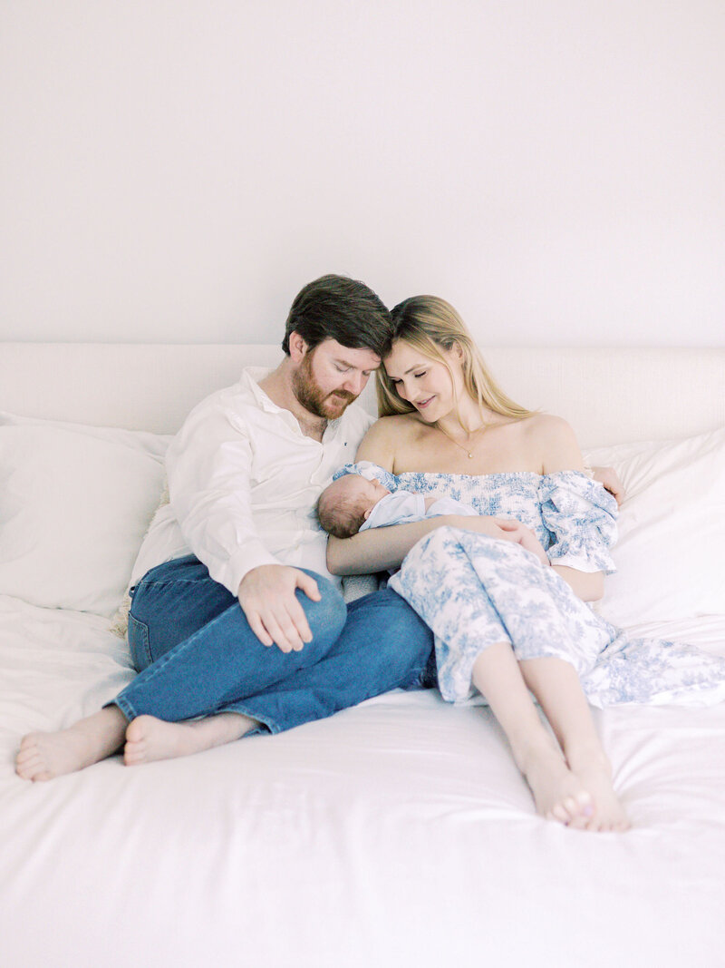 Couple holding baby on bed.